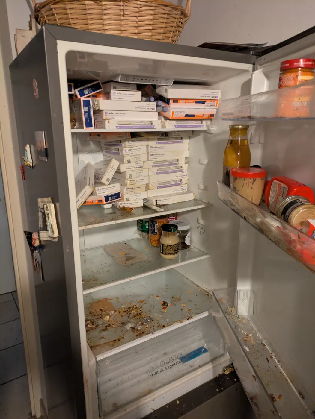 Réfrigérateur ouvert contenant des médicaments et des denrées, dans un logement à vider après un décès
