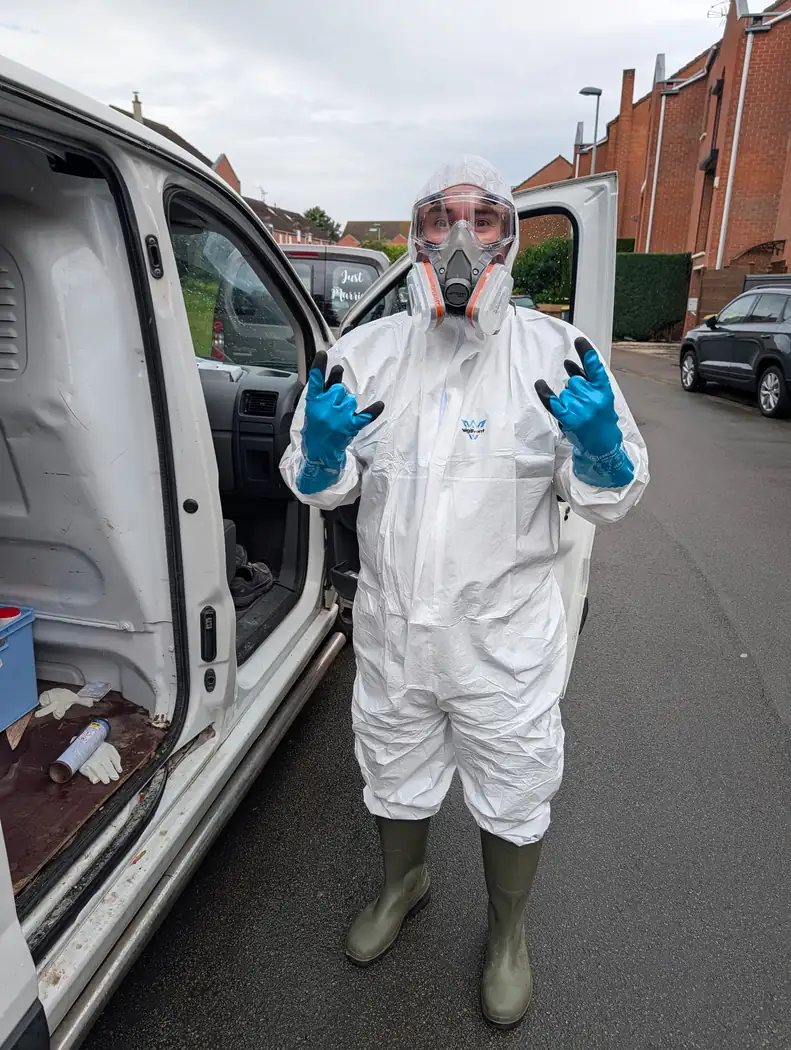 Intervenante de Soli'Débarras en combinaison, masque et gants, devant l'utilitaire de l'entreprise
