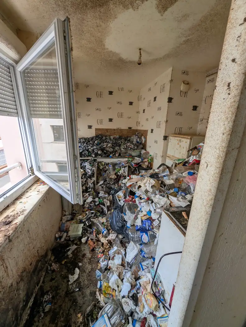 Cuisine dont le sol est entièrement recouvert de déchets, avec une importante trace de moisissure au plafond