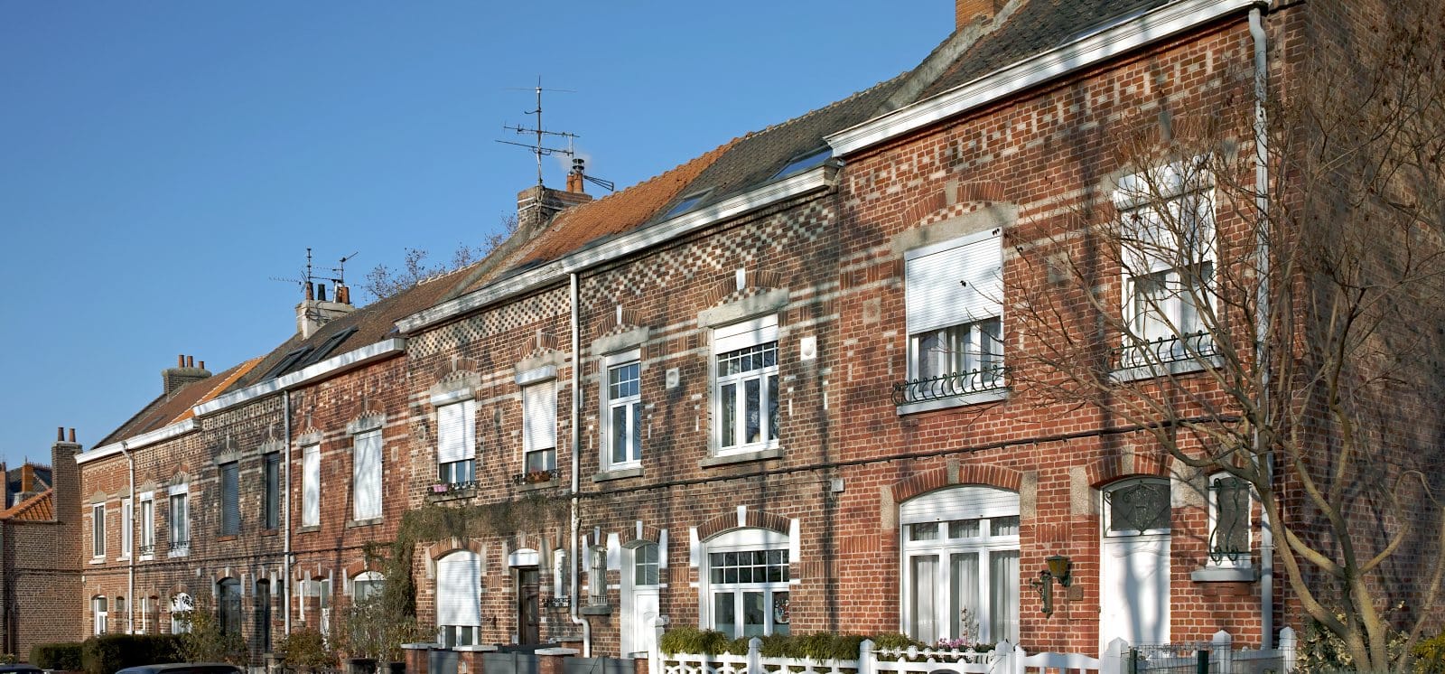 Rangée de maisons de ville en briques rouges rue Gustave-Scrive, à La Madeleine, sous un ciel bleu